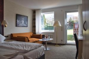 Habitación de hotel con cama, sofá y ventana en Hotel Quellenhof en Salzgitter