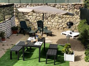 een patio met een tafel en stoelen en een parasol bij Casa Osiride con giardino privato e barbecue in Nulvi