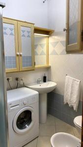 een badkamer met een wasmachine en een wastafel bij Casa Osiride con giardino privato e barbecue in Nulvi