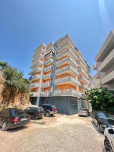 a large apartment building with cars parked in a parking lot at Gregor Apartments 1 in Sarandë