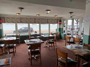 a restaurant with tables and chairs and a view of the ocean at Navigator Hotel in Bognor Regis