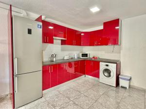 eine Küche mit roten Schränken und einer Waschmaschine in der Unterkunft Relax Beach House in Puerto de Santiago