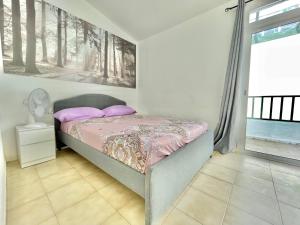 Schlafzimmer mit einem Bett mit rosa Kissen und einem Fenster in der Unterkunft Relax Beach House in Puerto de Santiago