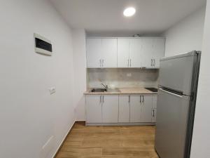a kitchen with white cabinets and a stainless steel refrigerator at Villa JIOTA in Ksamil