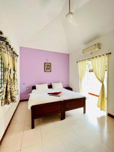 a bedroom with a bed and a purple wall at SkyView Villa in Candolim