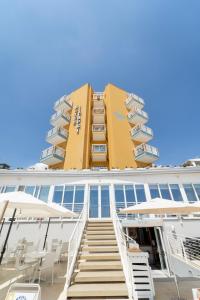 un edificio con escaleras y sillas delante en Hotel Capri 3 Stelle SUPERIOR, en Lido di Jesolo