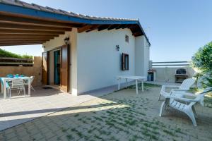 un patio con 2 sillas blancas y una mesa en Villino Turchese, en Cabras