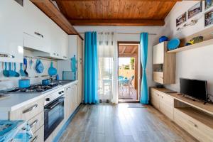 Una cocina con cortinas azules y una cocina con patio. en Villino Turchese, en Cabras