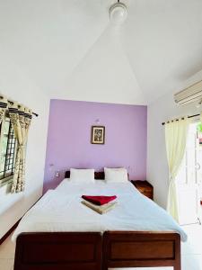 a bedroom with a bed with a purple wall at SkyView Villa in Candolim