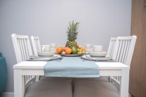 a white table with a bowl of fruit on it at Caroline Jacuzzi Apartments in Nowy Dwór Mazowiecki +17 photos