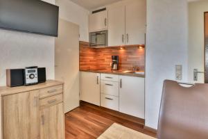 a small kitchen with white cabinets and a microwave at Terrassenhaus, FeWo 88 in Duhnen