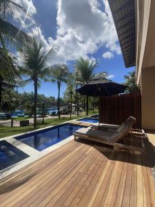 - une terrasse avec une chaise et un parasol à côté de la piscine dans l'établissement Carmel Cumbuco Resort, à Cumbuco