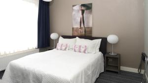 Un dormitorio con una cama blanca con almohadas y una pintura en B&B House No 7 en Ámsterdam