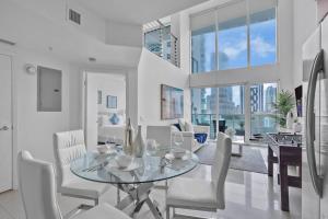 a dining room with a glass table and white chairs at Marvelous 2 bedroom Loft in Miami