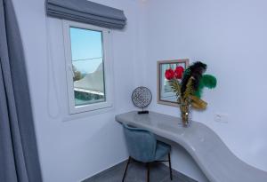 a white room with a table and a vase with flowers at Aegean Gold in Kamari