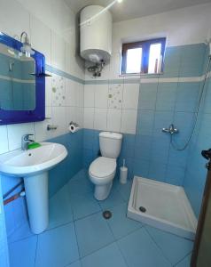 niebiesko-biała łazienka z toaletą i umywalką w obiekcie Blue Guesthouse w Gjirokastrze
