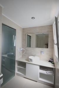 a white bathroom with a sink and a mirror at Mirabello Hotel in Heraklio Town
