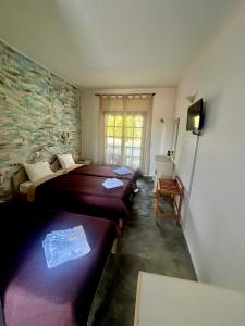 a room with two beds and a stone wall at Blue Garden Inn in Fourka