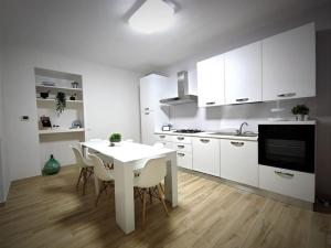 a white kitchen with a white table and chairs at la casa dei nonni in Musellaro