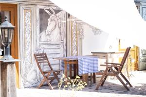 ein Esszimmer mit einem Tisch, Stühlen und einem Wandbild in der Unterkunft Maison d'hôtes du Mont in Morschwiller