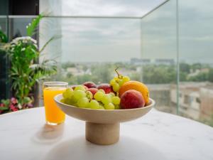 a bowl of fruit on a table with a glass of orange juice at The Heights of Sophistication - Panoramic Views in Bucharest
