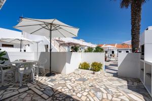 une terrasse avec une table et un parasol dans l'établissement Apartamentos Capitão by Umbral, à Porto Covo