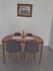 une table en bois avec quatre chaises et une photo sur le mur dans l'établissement Bel appartement meublé à Temara 10 minutes de la plage et 15 minutes du stade Prince Moulay Abdellah, à Oulad Kerroum