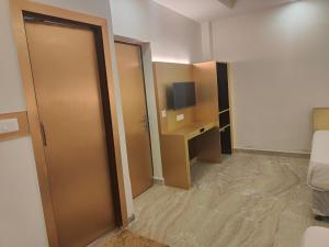 Habitación con puerta, escritorio y TV. en Hotel Nirmal Mahal - Paharganj - New Delhi, en Nueva Delhi