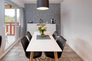 ドゥネンにあるTerrassenhaus, FeWo 45の黒い椅子と花瓶に飾られた白いダイニングテーブル