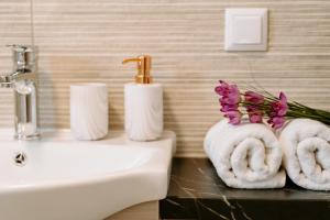 bagno con asciugamani e fiori su un lavandino di Apartments Christina a Perdika