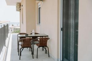 a balcony with a black table and chairs at Apartments Christina in Perdika