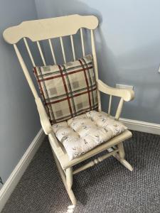 a wooden rocking chair with a plaid pillow on it at The Crewe Arms in Hinton in the Hedges