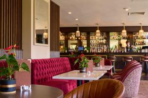 un restaurante con muebles rojos y un bar en Tulfarris Hotel and Golf Resort, en Blessington