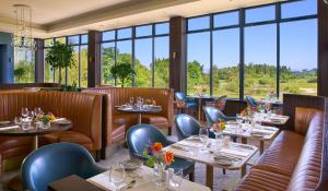 un restaurante con mesas, sillas y ventanas en Tulfarris Hotel and Golf Resort, en Blessington
