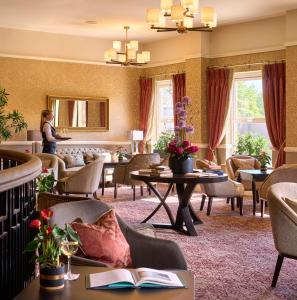 un vestíbulo de hotel con sillas y mesas y una mujer de pie en Tulfarris Hotel and Golf Resort, en Blessington
