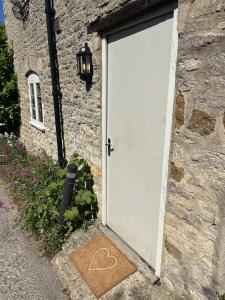 a white door of a stone building with a heart drawn on it at The Crewe Arms in Hinton in the Hedges