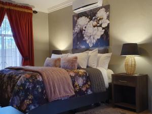een slaapkamer met een bed met een schilderij aan de muur bij The Village Inn in Polokwane