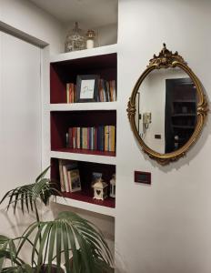 a mirror on a wall next to a shelf with books at CASA ODELLO suite and the sea in Bordighera