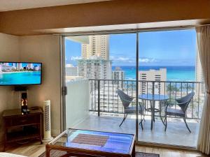 a room with a balcony with a table and a view of the ocean at Jenny's Cottage Waikiki in Honolulu