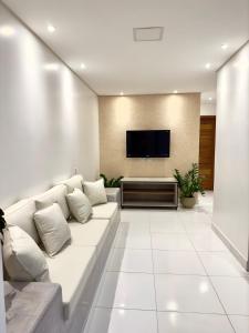 uma sala de estar com um sofá branco e uma televisão de ecrã plano em Acoara Beco Doce em Jericoacoara