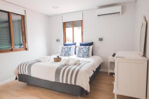 a white bedroom with a bed with blue pillows at Casa dos Avós - Folgosa Douro in Folgosa