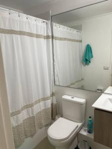 ein Badezimmer mit einem weißen WC und einem Spiegel in der Unterkunft Excelente departamento nuevo a pasos de la playa in La Serena