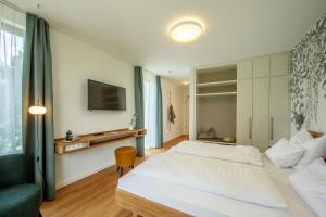 1 dormitorio con cama, sofá y TV en Seehörnle Bio Hotel & Gasthaus, en Gaienhofen