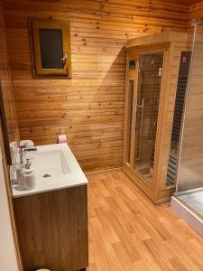 a bathroom with a sink in a wooden room at Romantique chalet avec sauna et jacuzzi extérieur in Arthon