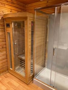 a walk in shower in a room with wooden walls at Romantique chalet avec sauna et jacuzzi extérieur in Arthon