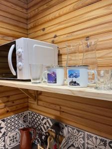 une étagère avec des tasses et des verres ainsi qu'un four micro-ondes dans l'établissement Romantique chalet avec sauna et jacuzzi extérieur, à Arthon