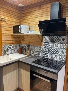 une cuisine avec un évier et un plan de travail dans l'établissement Romantique chalet avec sauna et jacuzzi extérieur, à Arthon 3 autres photos