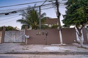 a house with a fence and a gate with a tree at Apto a 300 metro da praia - WIFI 200MB - Cozinha equipada - Ar condicionado in Rio das Ostras