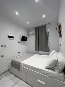 a white bedroom with a bed and a window at reAdy studio in Skiathos