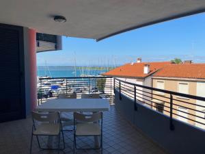 a table and chairs on a balcony with a view of the water at Costa Azzurra Aparment in Grado